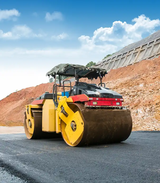 Heavy compactor roller smoothing new asphalt road surface in Arizona construction site