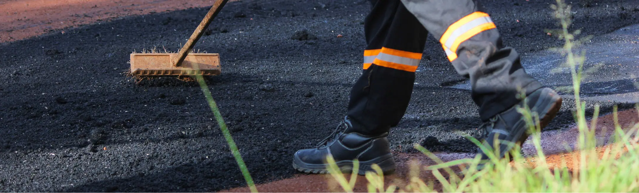 Worker spreading hot asphalt on a newly paved surface in Phoenix, Arizona