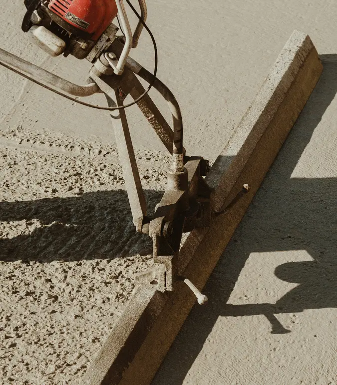 Concrete paving machine smoothing freshly poured concrete on a commercial project