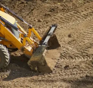 Construction vehicle performing grading to ensure proper site elevation and drainage