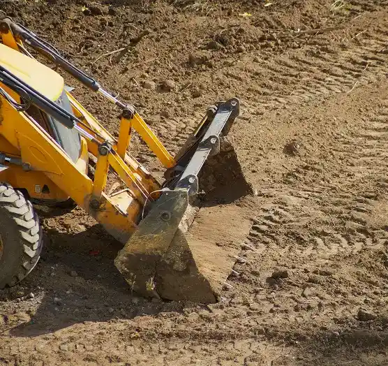 Construction vehicle performing grading to ensure proper site elevation and drainage