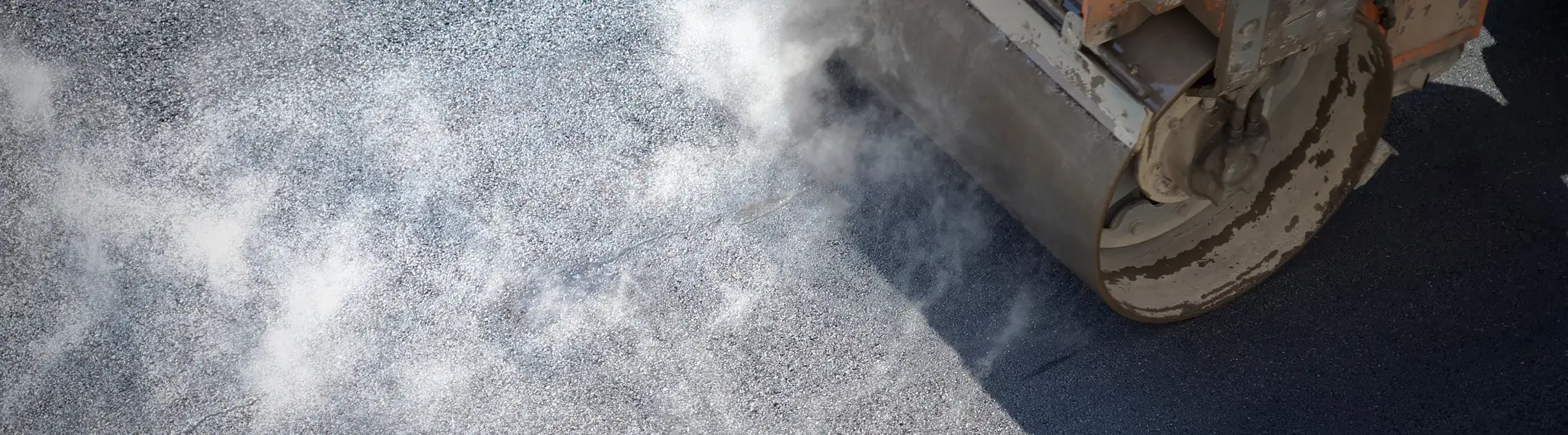 Steamroller compressing fresh asphalt on a road surface during paving operations in Arizona.
