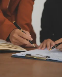 Government official signing paperwork at a desk.