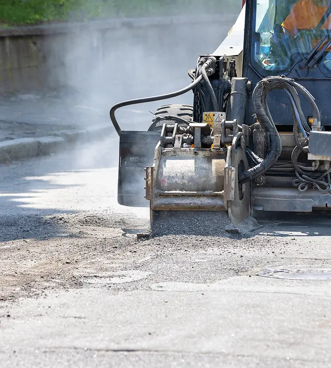 Asphalt milling machine removing the top layer of pavement in a parking lot to restore surface grade