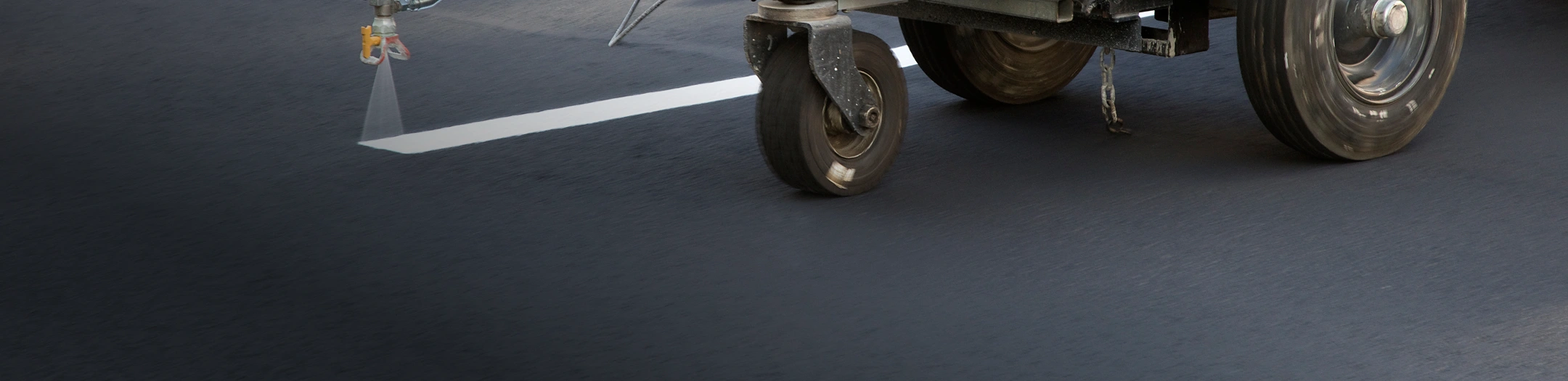 Close-up of a pavement striping machine applying fresh white lines on asphalt
