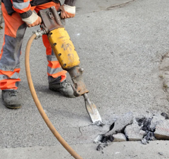 Demolition crew removing damaged asphalt pavement to prepare site for reconstruction.