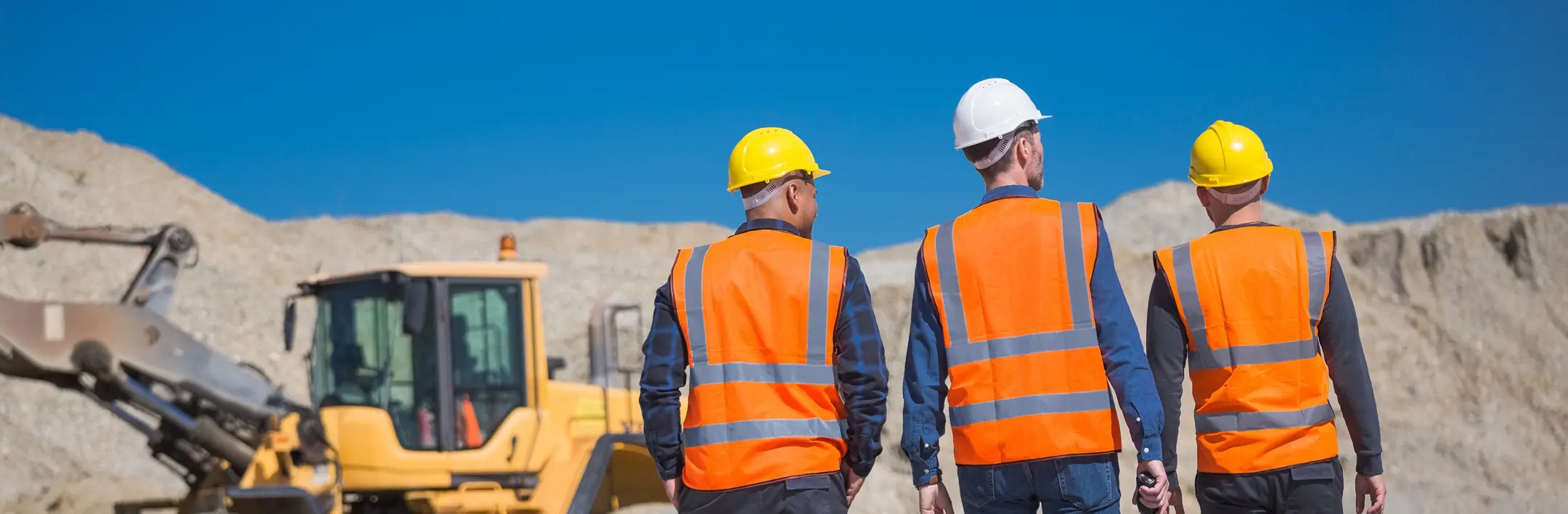 Construction workers in safety vests at job site with heavy machinery