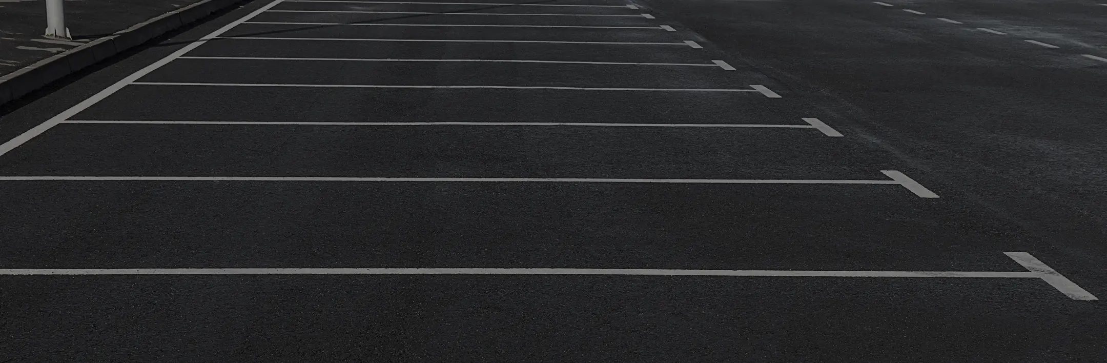 A freshly marked asphalt parking lot with white lines, photographed from ground level, emphasizing clean pavement and precise striping.