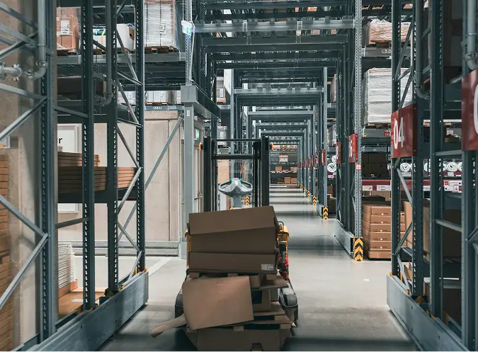 Interior of an industrial warehouse with concrete flooring and stacked packages on pallets, paved by Valor Pavement Solutions