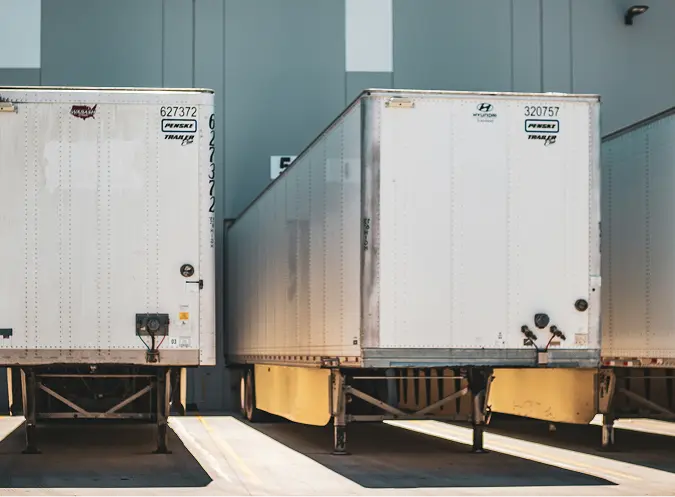 Two white semi-trailer trucks parked at an industrial loading dock in Arizona