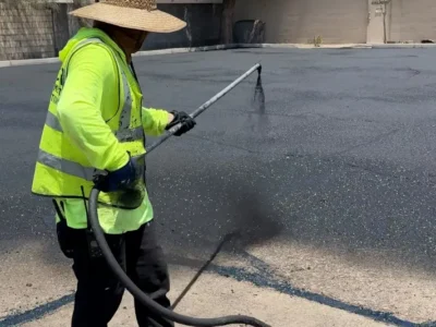Worker applying asphalt sealcoating during parking lot maintenance in Mesa, AZ