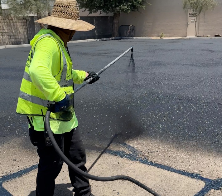 Worker applying asphalt sealcoating during parking lot maintenance in Mesa, AZ