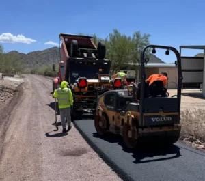 Worker operating Volvo asphalt roller during roadway paving project in Cave Creek, Phoenix, AZ.