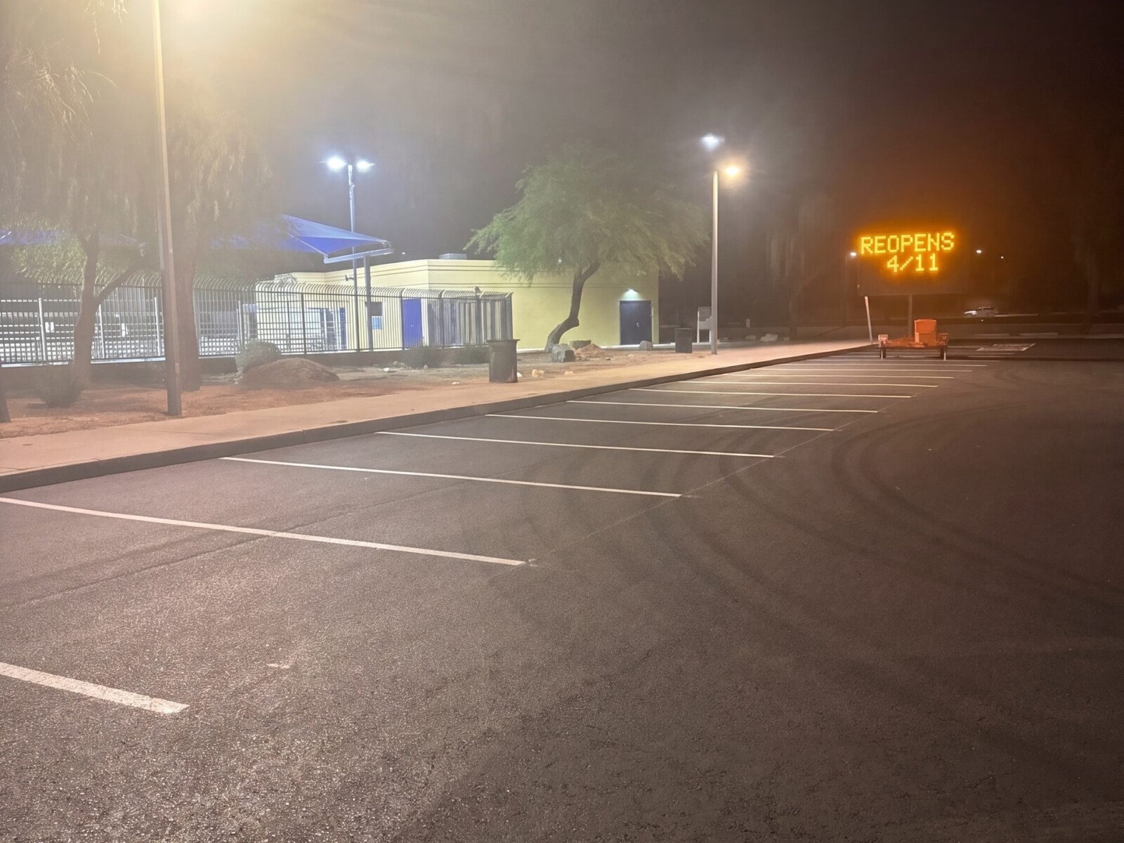Completed paving project at El Prado Park with REOPENS sign visible