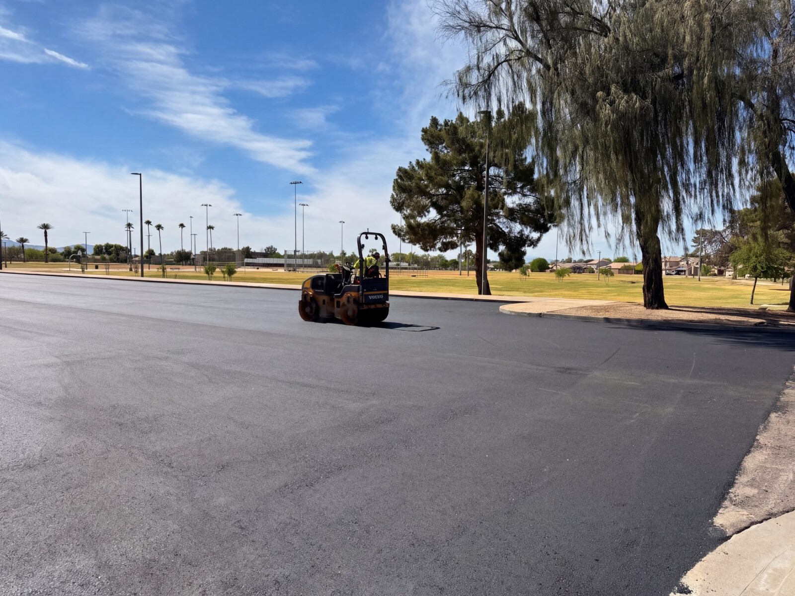 Steel-drum roller compacting fresh asphalt at El Prado Park parking lot in Phoenix