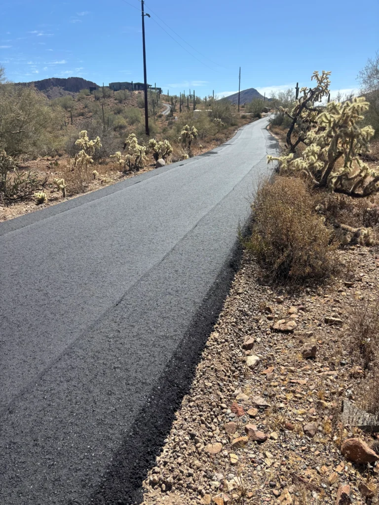 Newly paved roadway stretching through Desert Hills showing compacted asphalt surface with clean edges against desert terrain