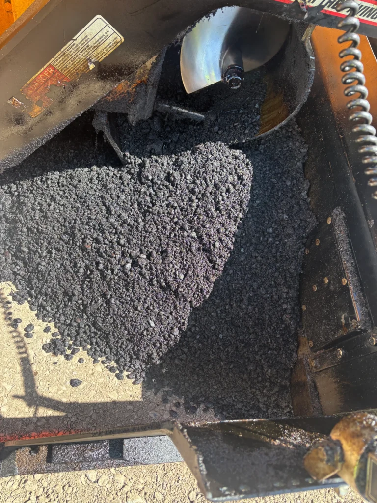Hot mix asphalt in paver hopper during new road paving in Desert Hills, AZ